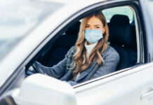 Eine junge Frau mit Schutzmaske im Auto