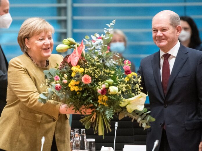 Angela Merkel freut sich über die Abschiedsblumen von Olaf Scholz.