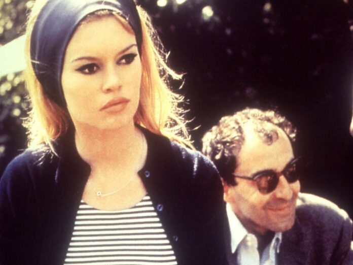 Regisseur Jean-Luc Godard sitzend hinter Brigitte Bardot am Set des Films 