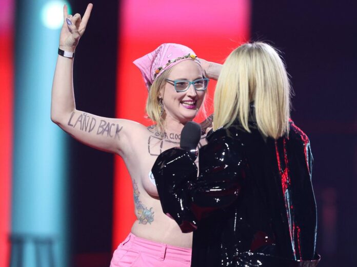 Avril Lavigne (re.) wollte die Oben-Ohne-Demonstrantin von der Bühne haben.