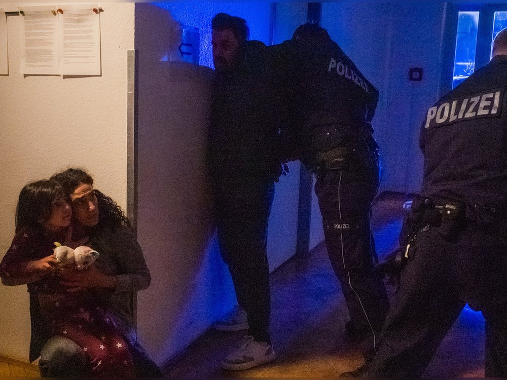 "XY gelöst - Mörderische Konflikte": Nachgestellte Szene. Eine Mutter umklammert ihre Tochter in einem dunklen Hausflur und blickt erschrocken zu zwei Polizisten hinauf
