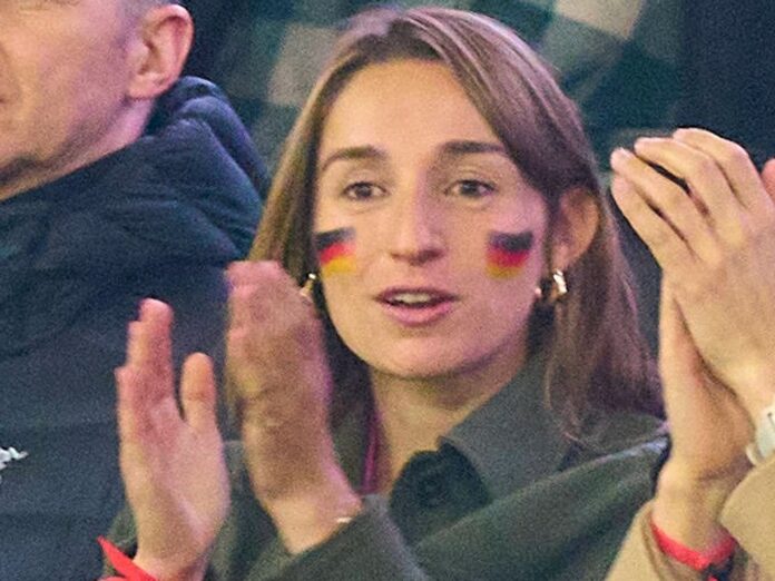 Lena Wurzenberger mit Deutschlandfahne im Gesicht und dem pinken Trikot unter ihrer Jacke beim Spiel gegen die Niederlande.